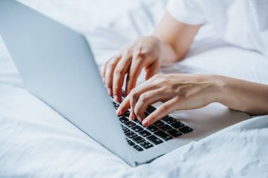 Yatağında dizüstü bilgisayar kullanan bir kadın
