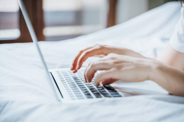 Yatağında dizüstü bilgisayar kullanan bir kadın