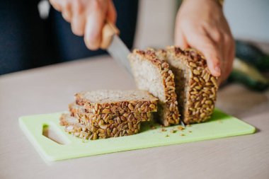 Tahtada tam tahıllı ekmek kesen kadın..