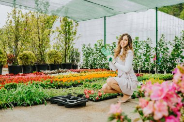 Genç, güzel kadın bahçıvan çiçek dikiyor, işinden zevk alıyor..