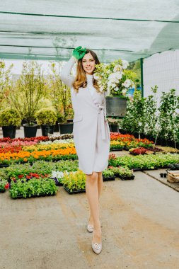 Genç, güzel bir kadın bahçıvan elinde çiçekler, işinden zevk alıyor..