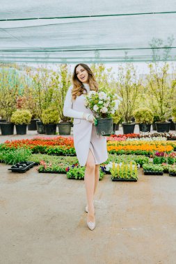 Genç, güzel bir kadın bahçıvan elinde çiçekler, işinden zevk alıyor..