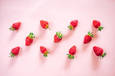 Açık pembe arka planda taze çilek deseni. Yukarıdan görüntüle.