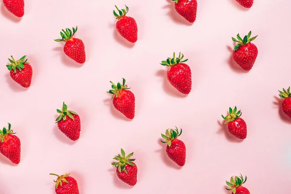 Açık pembe arka planda taze çilek deseni. Yukarıdan görüntüle.