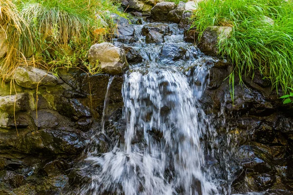 Небольшой водопад, вода течет над скалами, красивый природный фон — стоковое фото