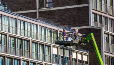 workers on a elevator platform, repairs on a apartment complex in the city of Amsterdam, The Netherlands