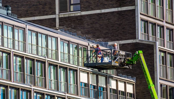 Travailleurs sur une plate-forme d'ascenseur, réparations sur un complexe d'appartements dans la ville d'Amsterdam, Pays-Bas — Photo