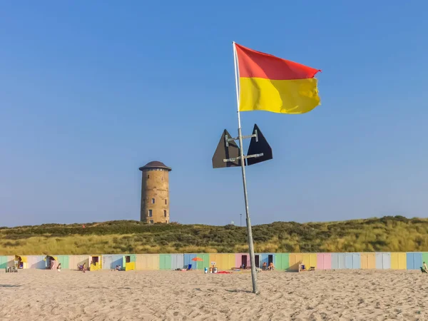 Agitant un drapeau rouge et jaune sur la plage de domburg, en Zélande, aux Pays-Bas, le 26 août 2019 — Photo