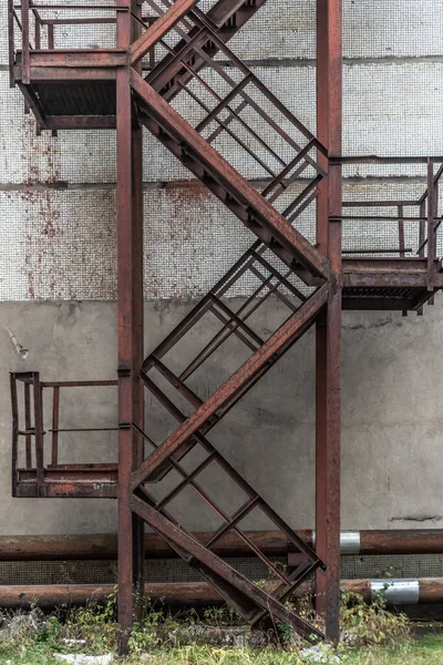 Fachada con escalera de acero de rescate de incendios de la antigua casa en fábrica, salida de incendios de la metalurgia de acero en la antigua pared de ladrillo blanco del edificio . —  Fotos de Stock