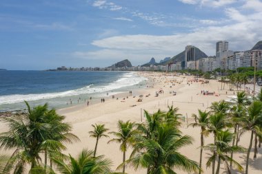 Ön planda palmiye ağaçları olan kumlu Copacabana plajının havadan görünüşü