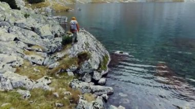 Kız gezgin dağ gölü ve dağların manzarasının tadını çıkarıyor. Dağlarda sonbahar. Yürüyüş. Atış serbest..