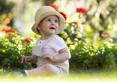 Güzel baharda bahçede çimlerin üzerinde oturan bebek.