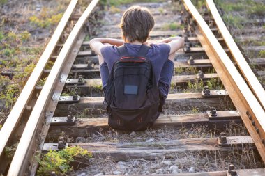 Yalnız bir çocuk raylarda oturur