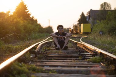 Çocuk raylarda yürüyor.