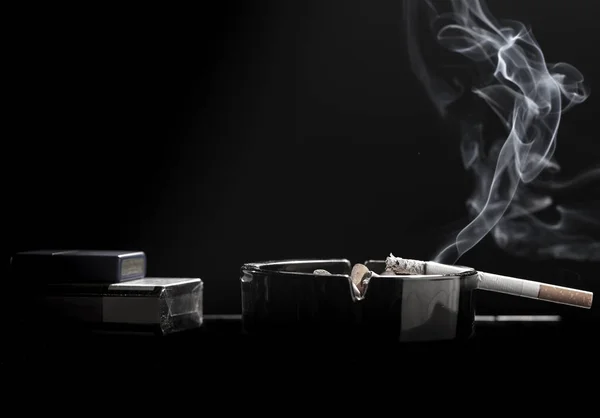 Nahaufnahme einer Zigarette auf dem Aschenbecher mit einem schönen Hauch von Rauch — Stockfoto
