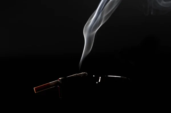 Närbild av cigarett på askfat med en vacker wisp av rök — Stockfoto