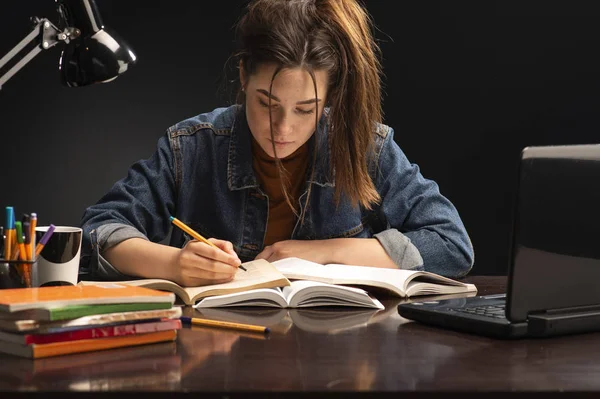 Kız masada oturuyor ve ders çalışıyor.