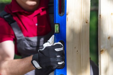 Young carpenter measuring wood using water spirit level in his w