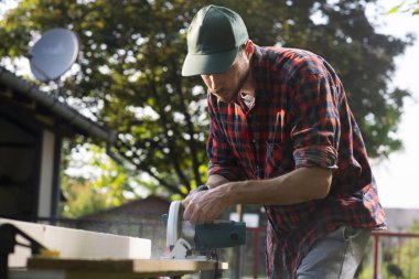 Carpenter using circular saw cutting wooden boards 