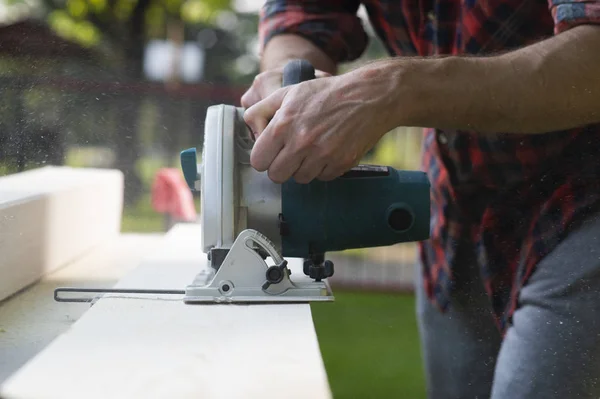Carpenter using circular saw cutting wooden boards — Stock Photo, Image