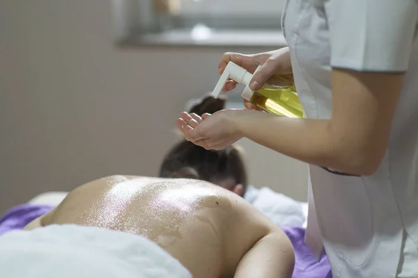 Young woman receiving a back massage in a spa center. Female patient is receiving treatment by professional therapist