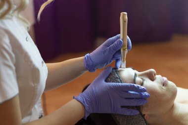 Spa, tatil köyü, güzellik ve sağlık konsepti. Güzellik salonunda yüz bakımı gören güzel bir kadın. Yüz bakımı. Kozmetoloji 