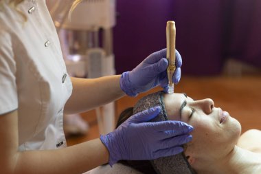 Spa, tatil köyü, güzellik ve sağlık konsepti. Güzellik salonunda yüz bakımı gören güzel bir kadın. Yüz bakımı. Kozmetoloji 