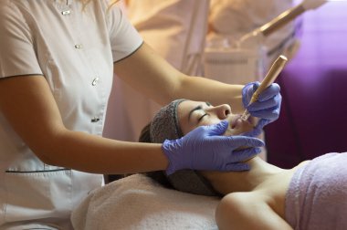 Spa, tatil köyü, güzellik ve sağlık konsepti. Güzellik salonunda yüz bakımı gören güzel bir kadın. Yüz bakımı. Kozmetoloji 