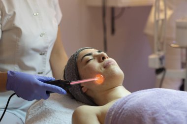 Spa, tatil köyü, güzellik ve sağlık konsepti. Güzellik salonunda yüz bakımı gören güzel bir kadın. Yüz bakımı. Kozmetoloji 