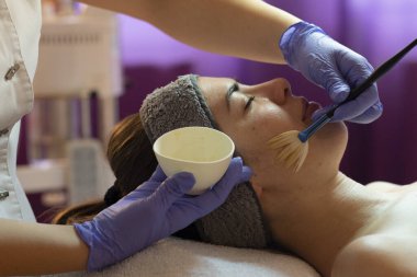 Spa, tatil köyü, güzellik ve sağlık konsepti. Güzellik salonunda yüz bakımı gören güzel bir kadın. Yüz bakımı. Kozmetoloji 