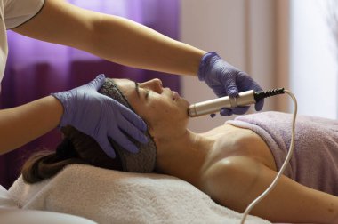 Spa, tatil köyü, güzellik ve sağlık konsepti. Güzellik salonunda yüz bakımı gören güzel bir kadın. Yüz bakımı. Kozmetoloji 