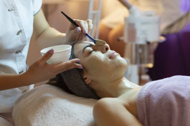 Yüz soyma maskesi, kaplıca güzellik tedavisi, cilt bakımı. Güzellik salonundaki kadın yüz bakımını alıyor. Yan görüş, yakın çekim.