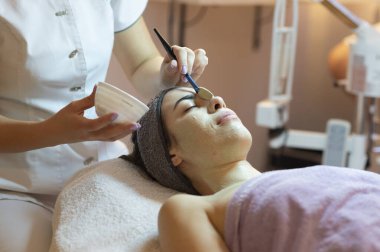 Yüz soyma maskesi, kaplıca güzellik tedavisi, cilt bakımı. Güzellik salonundaki kadın yüz bakımını alıyor. Yan görüş, yakın çekim.