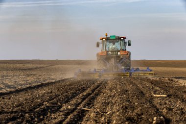 Traktör tarlada çalışıyor, tarlayı ekime hazırlıyor, tarlayı sürüyor.