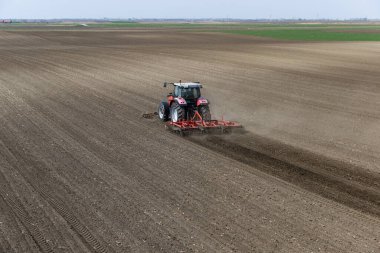 Traktör tarlada çalışıyor, tarlayı ekime hazırlıyor, tarlayı sürüyor.