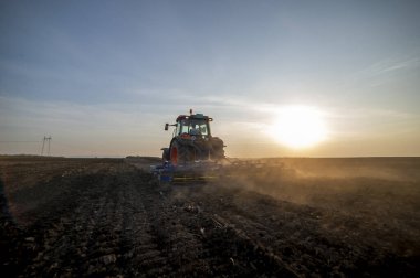 Traktör tarlada çalışıyor, tarlayı ekime hazırlıyor, tarlayı sürüyor.