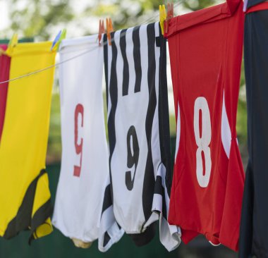 Çamaşır ipinde kurutmak için asılı renkli kıyafetler. Futbol formaları.