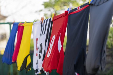 Çamaşır ipinde kurutmak için asılı renkli kıyafetler. Futbol formaları.