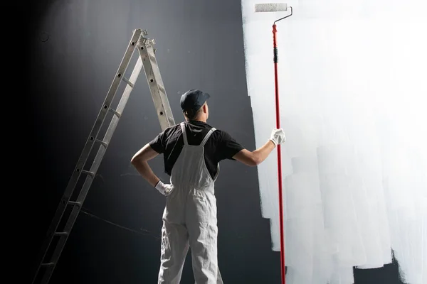 Pintor Masculino Uniforme Olha Para Parede Segurando Rolo Construção — Fotografia de Stock