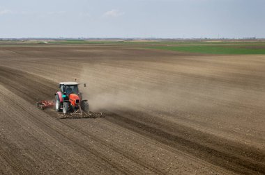 Traktör tarlada çalışıyor, tarlayı ekime hazırlıyor, tarlayı sürüyor.
