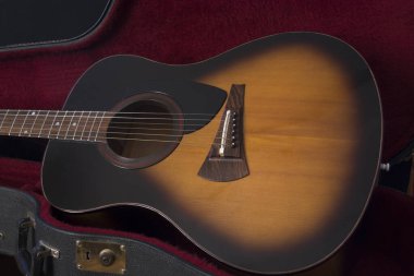 Altı telli akustik gitarın doğal ışık altında siyah arka planda bir parçası..