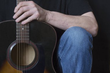 Gündüz vakti gitarist Iruk 'un altı telli akustik gitaristinin siyah arka plandaki bir parçası..