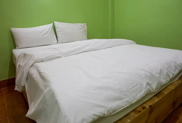 Un lit non fait avec fond de lin blanc vert — Photo