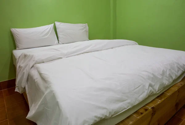 An unmade bed with white linens background green — Stock Photo, Image