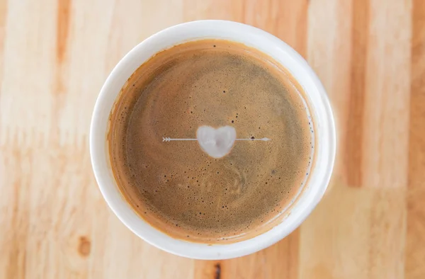 Herz in Tasse Kaffee mit in einer weißen Tasse auf Holzgrund. — Stockfoto