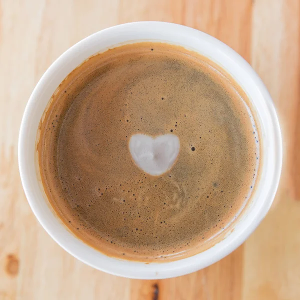Herz in Tasse Kaffee mit in einer weißen Tasse auf Holzgrund. — Stockfoto