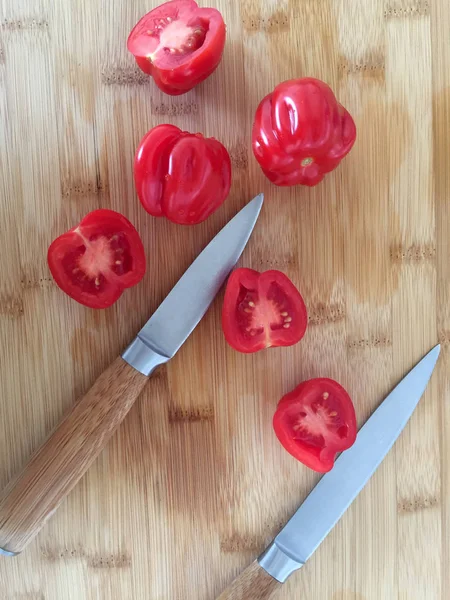 Tomatoes on the bamboo board with knives