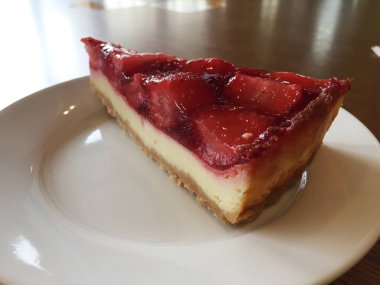 Beyaz tabakta çilekli cheesecake dilimi.