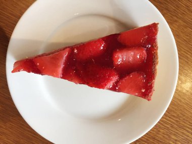 Beyaz tabakta çilekli cheesecake dilimi.