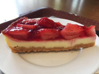 Beyaz tabakta çilekli cheesecake dilimi.